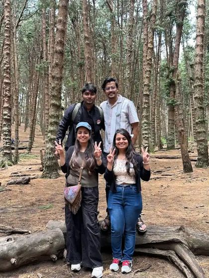 Friends posing on a log in the pine forest.