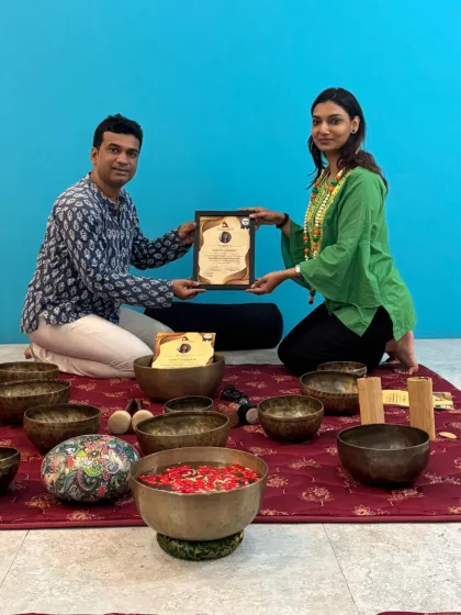 A student smiles as she receives her sound healing certification, a symbol of her dedication and newly acquired expertise.