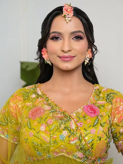 A beautiful portrait of the bride, smiling and confident. The makeup is fresh, fun, and perfect for a daytime event like Haldi or Mehendi.