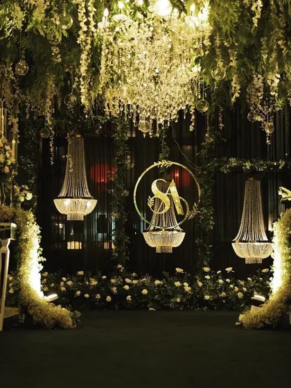 The full view of the photo-op area within the floral entrance, showing how the hanging chandeliers and custom monogram create a perfect, beautifully lit backdrop for pictures.
