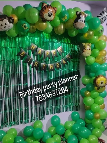 A simple and effective jungle theme decoration for a home party, using a green fringe curtain and a balloon arch with animal foil balloons.