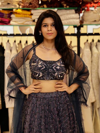 Here is a front view of the deep blue lehenga, worn with a sheer, feather-trimmed cape. This accessory adds an extra layer of drama and sophistication to the outfit.