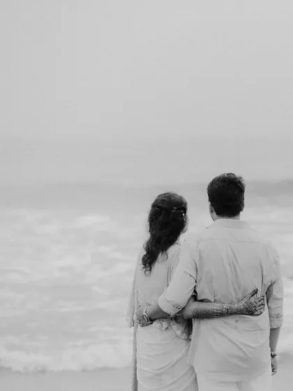 A serene black and white portrait of a couple looking out at the sea. This image evokes a sense of peace, togetherness, and looking toward a shared future.
