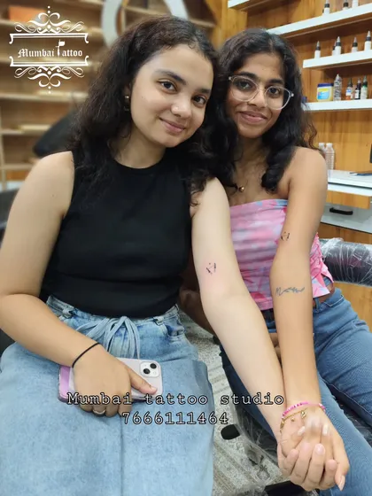 Two best friends celebrating their new tattoos at our studio. The experience of getting inked together is often as meaningful as the tattoos themselves.