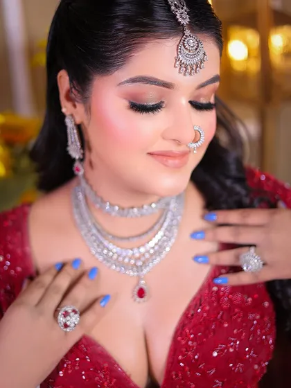 This portrait highlights the stunning layered necklace and detailed eye makeup, with a soft, elegant pose.