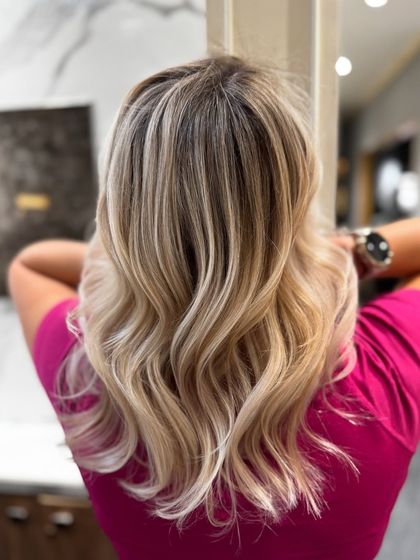 This shot captures the full, voluminous look of the pearl blond balayage, styled in beautiful waves.
