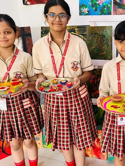 Three students hold up the decorative puja thalis they prepared for the Diwali competition. This activity allows them to express their creativity while learning about cultural traditions.
