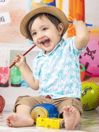 A happy little guy enjoying the beach theme, playing with his toys in the "sand".
