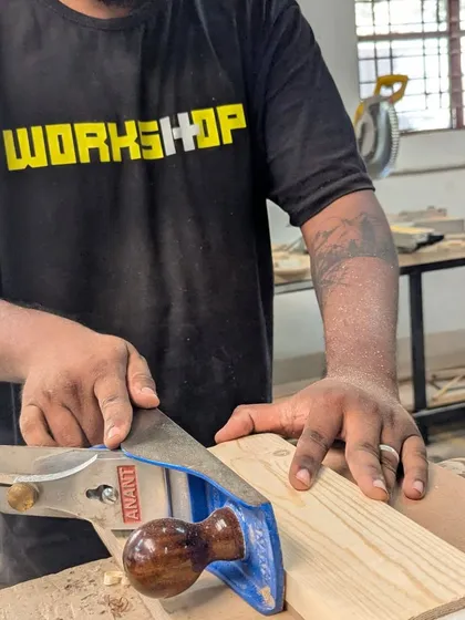 Using a hand planer to smooth the surface of a pine board. Even in our power tool workshop, we mix in essential hand tool skills for that perfect finish.