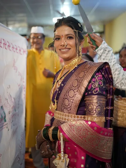 The bride during the Antarpat ritual, looking happy and excited. Her makeup is flawless, ready for the big reveal.