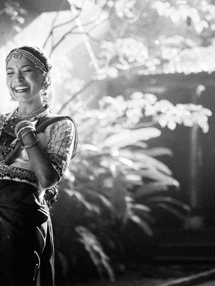 A black and white photo capturing the timeless laughter of a bride during her cross-cultural wedding celebration.