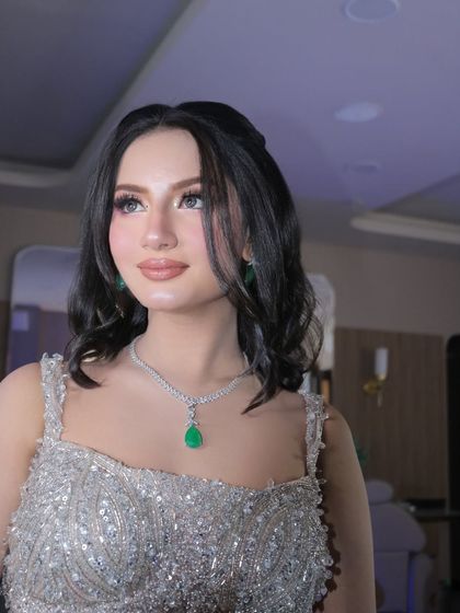 A close-up portrait of this stunning engagement bride. The focus is on her flawless skin and the beautifully blended eye makeup that complements her emerald jewelry.