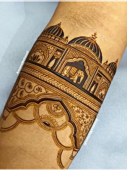 A detailed close-up of a palace design on the arm. The intricate jharokhas, domes, and elephant motifs showcase the precision of the artwork.