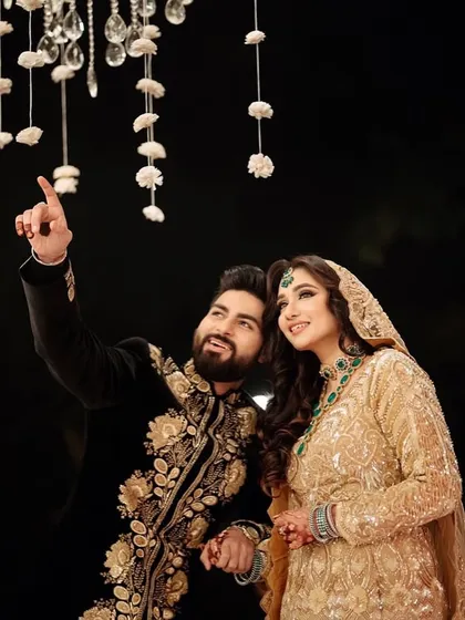 A magical moment under the lights. The couple's coordinated gold and black outfits create a look of pure luxury and romance.