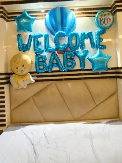 A simple yet sweet bedroom decoration to welcome a new baby, with "Welcome Baby" foil balloons and other themed foils over the bed.