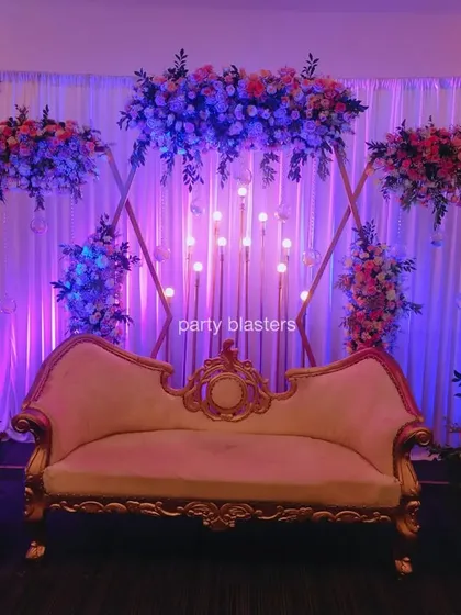 An elegant stage for a wedding anniversary. The design features a geometric gold frame, beautiful floral arrangements, and soft lighting for a romantic and sophisticated look.