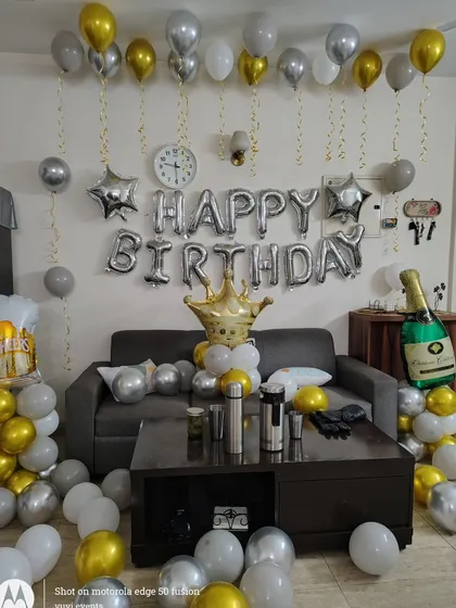 A simple and elegant birthday room decoration with silver, gold, and white balloons, and fun props like beer and champagne foil balloons.