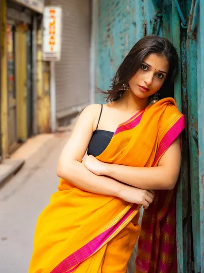 Leaning against a wall in a narrow lane, this portrait has a relaxed yet direct feel. The out-of-focus background hints at the city's depth.