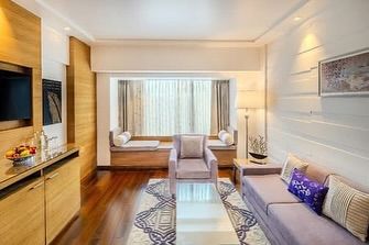 For the Taj Vivanta in Goa, we designed suite rooms that capture a contemporary coastal charm. This living area features a soft lilac sofa, a bay window seating nook, and a custom-designed rug, all in a calming, sophisticated palette.