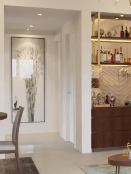 This compact home bar is seamlessly integrated into the living area. The design features a rich wood cabinet, a herringbone tile backsplash, and elegant brass-finished shelves, creating a chic and functional corner for entertaining.