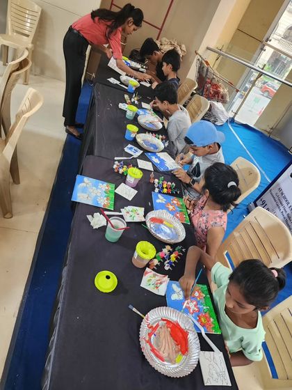 A long table of children deeply engaged in painting. The focus and quiet creativity in this moment is beautiful to witness.