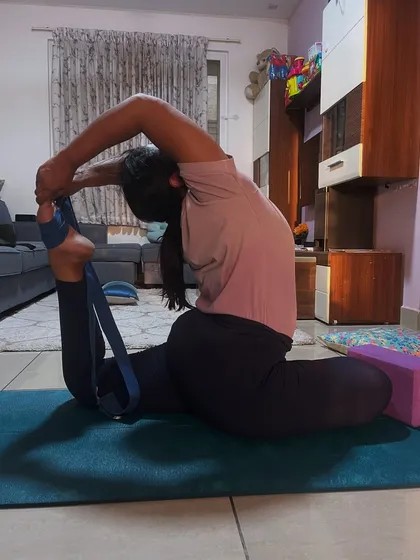 A student using a strap to deepen her Rajakapotasana, or king pigeon pose. Props are not a crutch but a tool to help us practice with better alignment and go deeper safely.