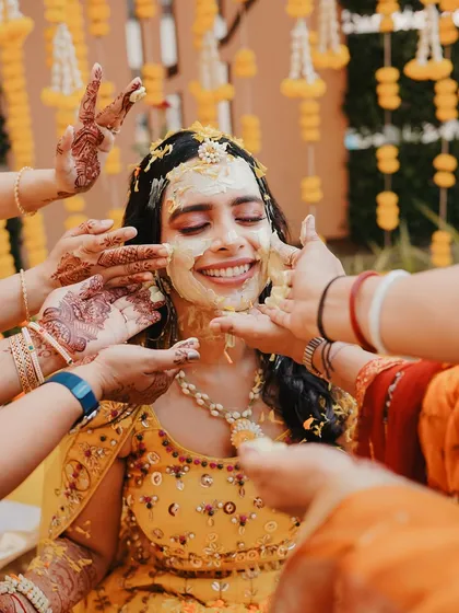The Haldi ceremony is about unrestrained joy, and we love capturing it. This candid shot, with hands lovingly applying turmeric to the bride's smiling face, freezes a moment of pure, unscripted happiness.