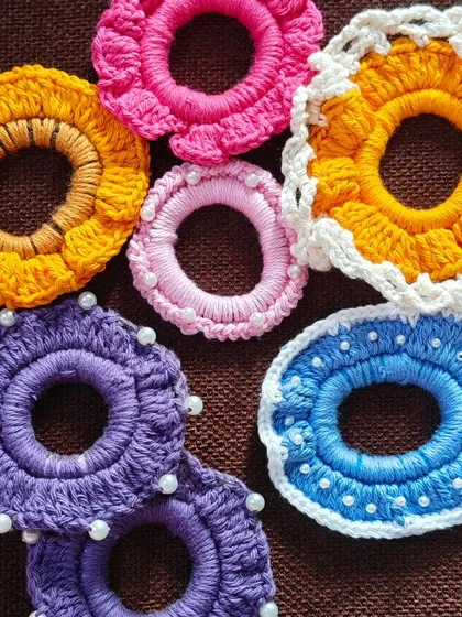 A colorful assortment of my floral and pearl-detailed crochet scrunchies. I make them in various designs, including sunflower patterns, simple ruffles, and ones dotted with tiny pearls for a touch of elegance.