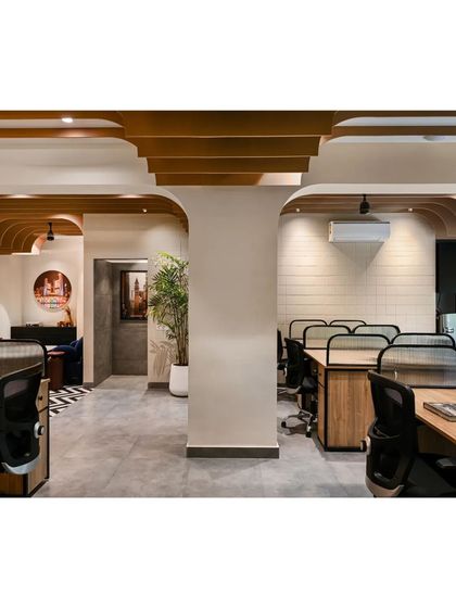 This view shows how we used arched beams and ceiling fins to frame views and connect different zones within the open-plan office. The design conceals structural beams while adding depth and character.