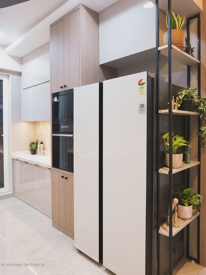 The kitchen at Sai World Empire features a tall unit for a built-in oven and microwave, along with open shelving for plants. This design combines efficient appliance integration with decorative touches.