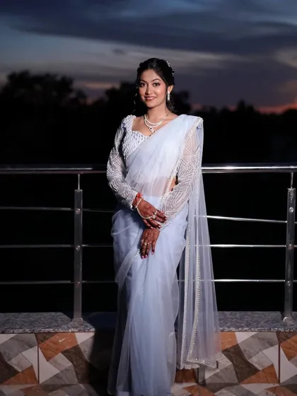 The bride posing against the twilight sky. Her ethereal look is enhanced by a soft, glowing makeup application and a beautiful powder blue saree.