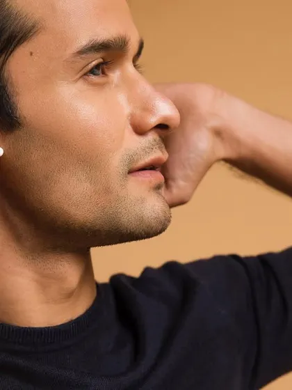 A classic studio headshot for Crossbeats, featuring their white wireless earbuds. The neutral background and clear lighting ensure the product is the hero, while the model's engaged expression suggests a high-quality listening experience.