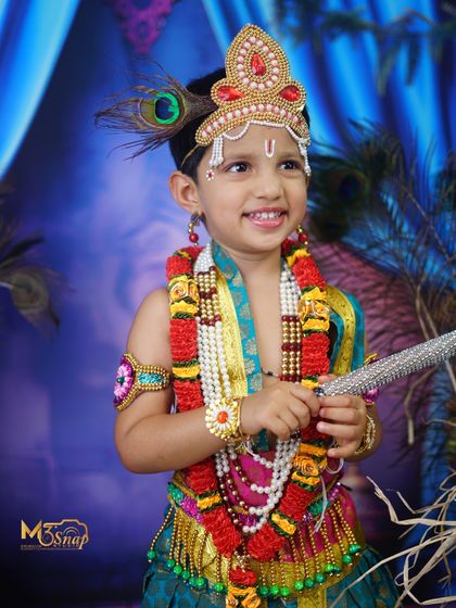 A joyful and bright portrait of a child in a Krishna costume. His happy smile and sparkling eyes truly bring the character to life.