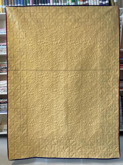 The back of the silk Jacob's Ladder quilt, showing a rich gold fabric and the detailed quilting.
