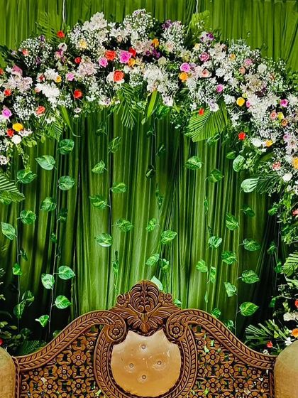 A close-up of a green-themed engagement backdrop. The floral arch and hanging leaves create a fresh and natural ambiance, perfect for a daytime ceremony.