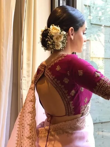 A side view of a bride with a floral bun, showing how the hairstyle can be both soft and structured. It's a perfect choice for a classic bridal look.