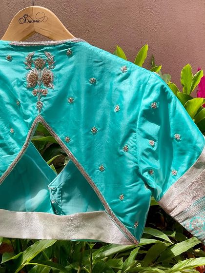 The back of the turquoise patchwork blouse, featuring a triangular cutout and a delicate embroidered motif.