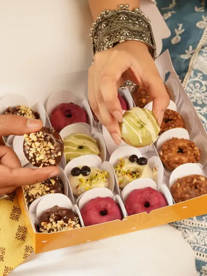 A box of assorted mini doughnuts being shared, a modern and fun treat for Raksha Bandhan celebrations.