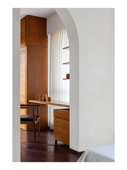 A study area seen through an archway, featuring a custom floor-to-ceiling wardrobe and desk unit. I design integrated furniture to make the most of a room's dimensions, creating a seamless and highly functional space.