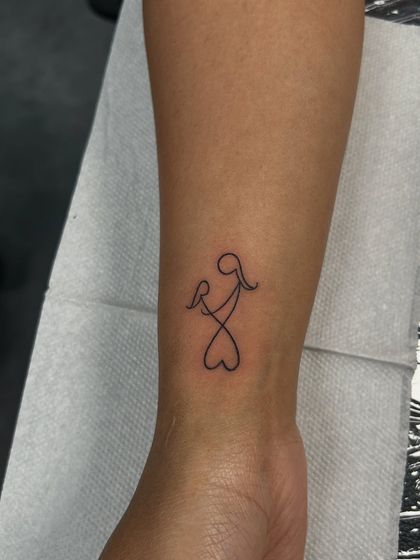A beautiful single-line tattoo of a mother holding a child, forming a heart at the bottom. This minimalist design is a powerful symbol of a mother's endless love.