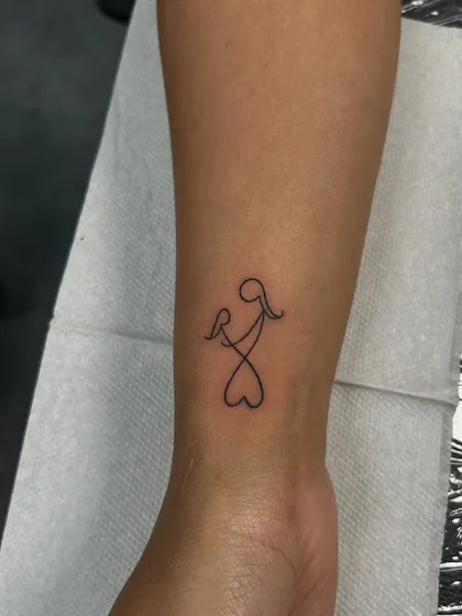 A beautiful single-line tattoo of a mother holding a child, forming a heart at the bottom. This minimalist design is a powerful symbol of a mother's endless love.
