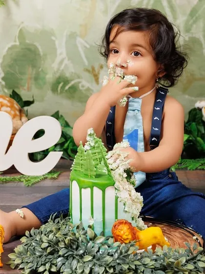 The aftermath of a fun cake smash! This little boy is covered in cake and happiness after his jungle-themed celebration.