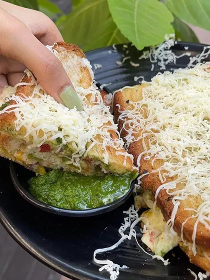 Dipping a piece of my classic veg cheese grill sandwich into our fresh green chutney. It's a perfect combination.