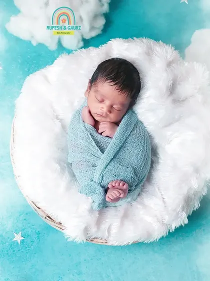Floating on a cloud. This creative setup uses a fluffy white basket against a dreamy blue sky backdrop to create a magical portrait of a sleeping newborn.