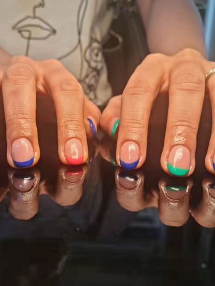 A vibrant multi-color French manicure, with each nail tip painted in a different bold color like red, blue, and green.