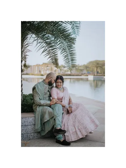 A peaceful portrait of a couple sitting by the water's edge. The serene setting and their relaxed posture create a feeling of calm and contentment, perfect for a tranquil pre-wedding session.