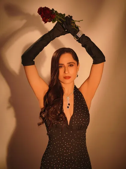 A powerful and artistic pose. Holding the rose aloft creates a dramatic silhouette, highlighting the elegant lines of the dress and the contrast of the black gloves.