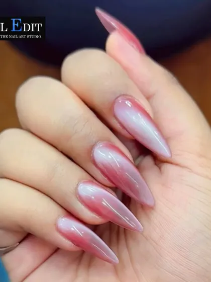 This close-up shows a beautiful pink and white cat-eye effect on long stiletto nails. The soft, blended colors and magnetic shimmer create a delicate yet captivating look.