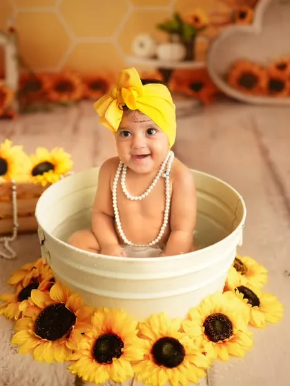 Accessorized with a pearl necklace and a bright yellow bow, this baby is all smiles in her sunflower-themed tub session. We provide all the cute accessories for the shoot.