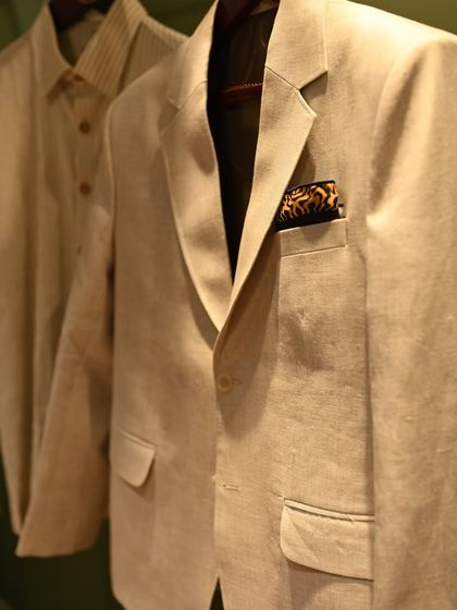 A closer view of the beige linen jacket reveals the texture of the fabric and the sharp cut of the lapel. A patterned pocket square adds a point of interest, illustrating the 60-30-10 rule in practice.